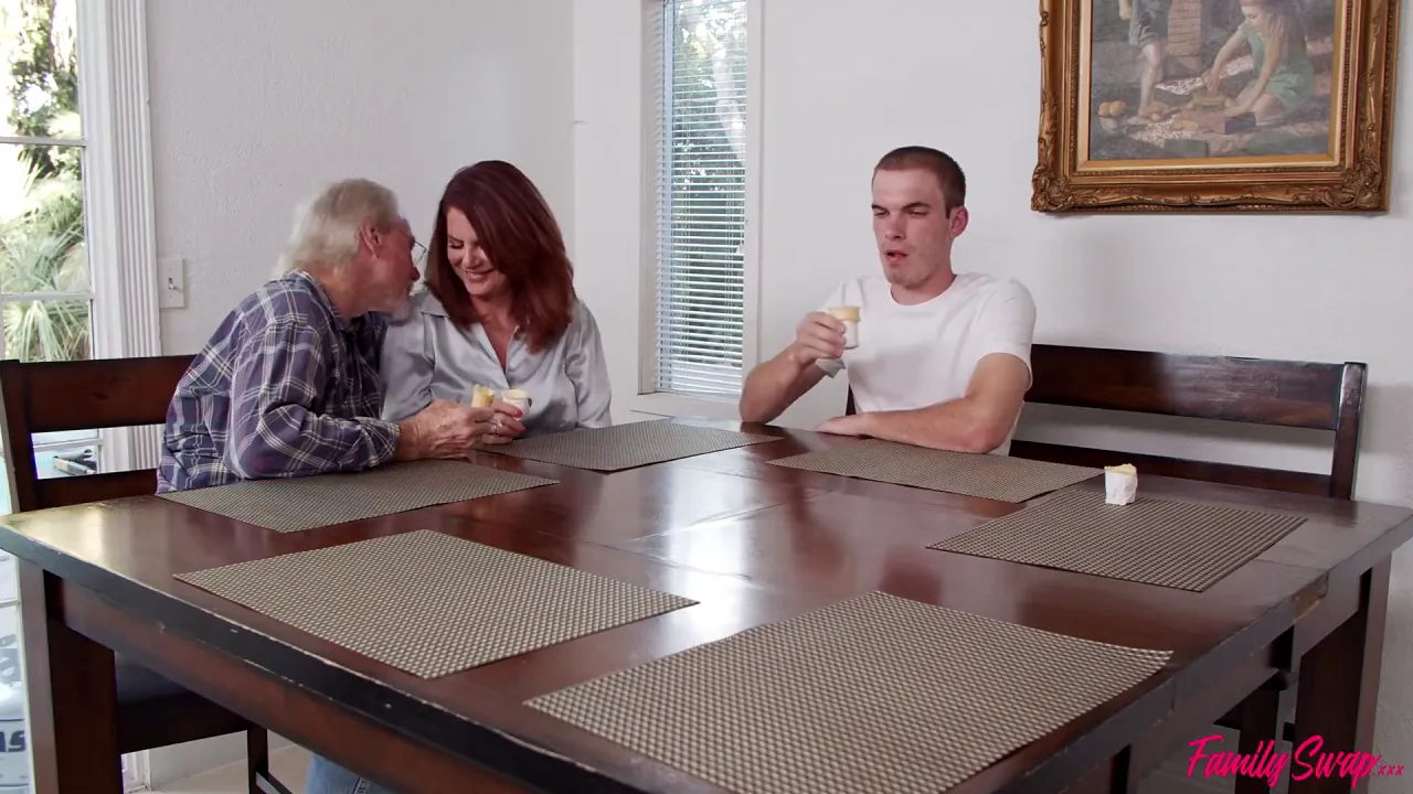 MILF redhead Andi James has group sex with petite partner Jessae Rosae, two men on a sofa